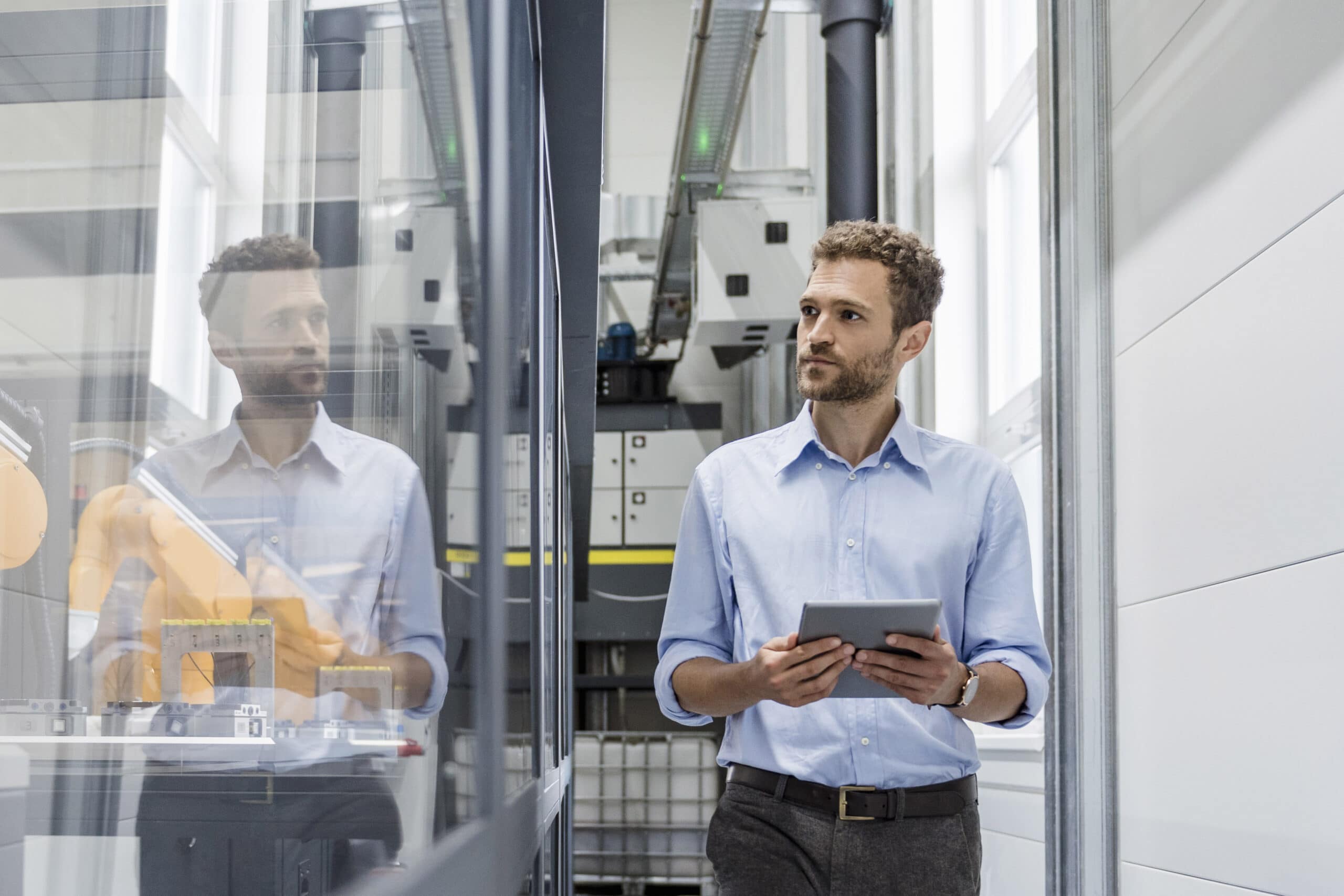 Businessman checking robots with digital tablet in high tech company FULL LENGTH OF A MAN WORKING AT GLASS